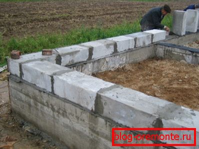 Instalación de la primera fila de bloques de espuma sobre una base de tiras de concreto Instalación de la primera fila de bloques de espuma sobre una base de tiras de concreto
